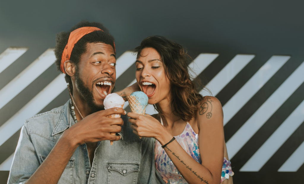 Photo of couple eating ice cream cones together.